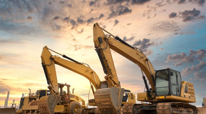 Zwei gelbe Bagger auf einer Baustelle vor einem Sonnenuntergangshimmel.