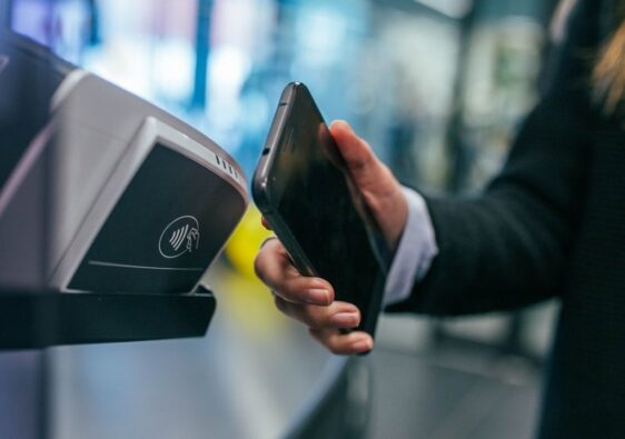 Smartphone wird an einem Lesegerät für kontaktloses Bezahlen gehalten
