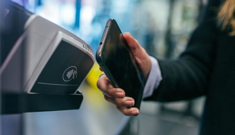 Smartphone wird an einem Lesegerät für kontaktloses Bezahlen gehalten