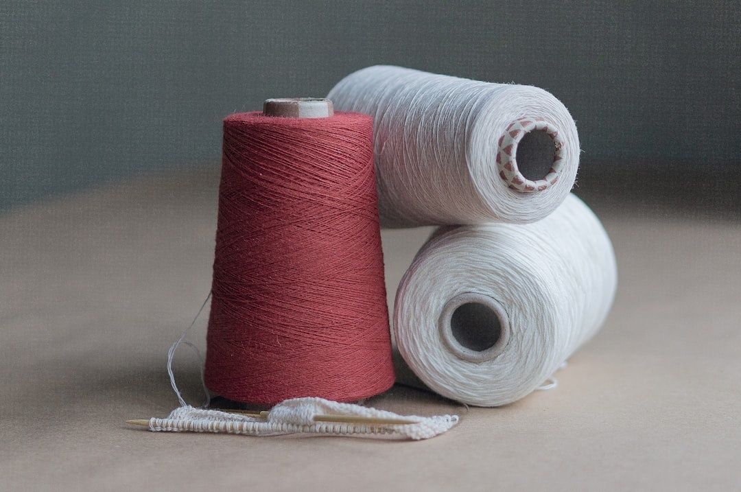 Rote und weiße Garnspulen mit einem gestrickten Textilstück